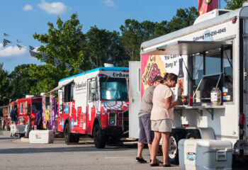 row of colorful food trucks serving customers