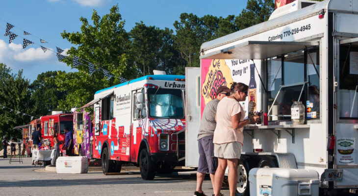 row of colorful food trucks serving customers