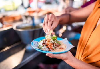 woman wearing an orange dress eating a taco on a blue plate