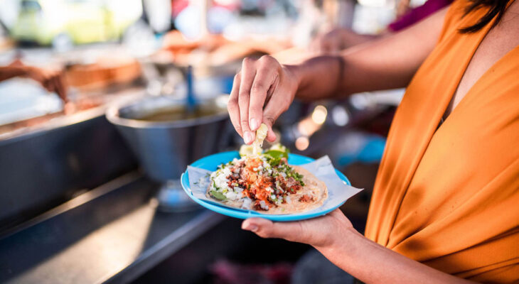 woman wearing an orange dress eating a taco on a blue plate