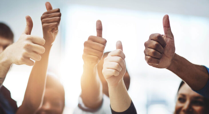 diverse group of people doing thumbs up indicating success