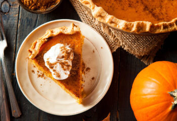 pumpkin pie on a plate on a dark wooden table