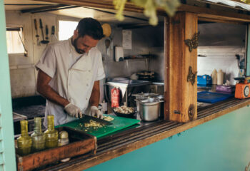 food truck owner chopping ingredients inside a turquoise rustic-themed food truck