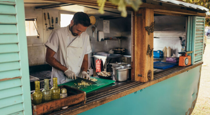 food truck owner chopping ingredients inside a turquoise rustic-themed food truck