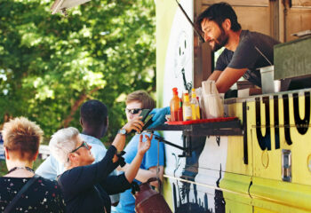 customer being served by a man inside a yellow-colored food truck