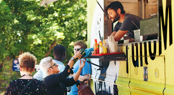 customer being served by a man inside a yellow-colored food truck