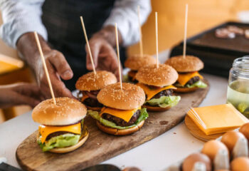 six hamburgers in a stick served on a wooden plate