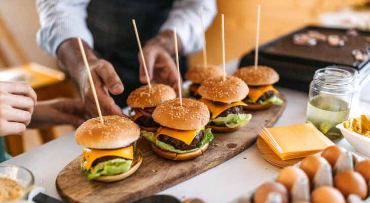six hamburgers in a stick served on a wooden plate