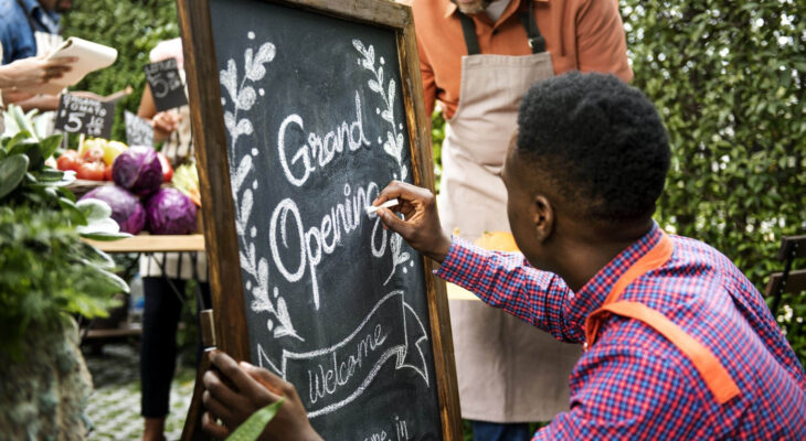 food truck owner designing a grand opening sign on a chalkboard