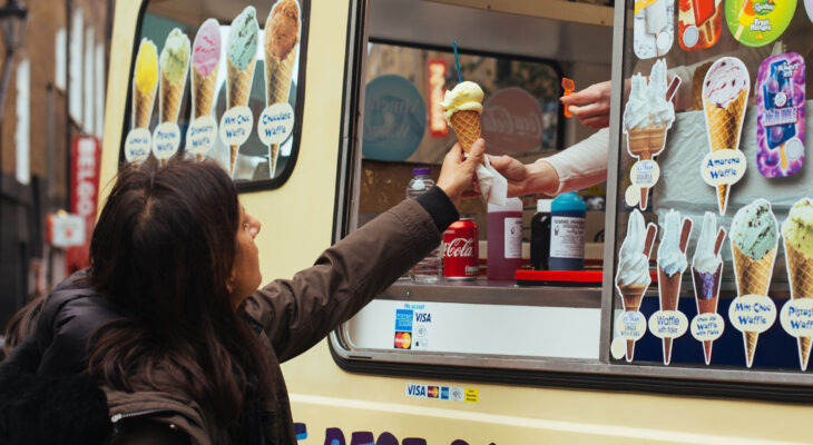 ice cream truck owner handing ice cream to a customer