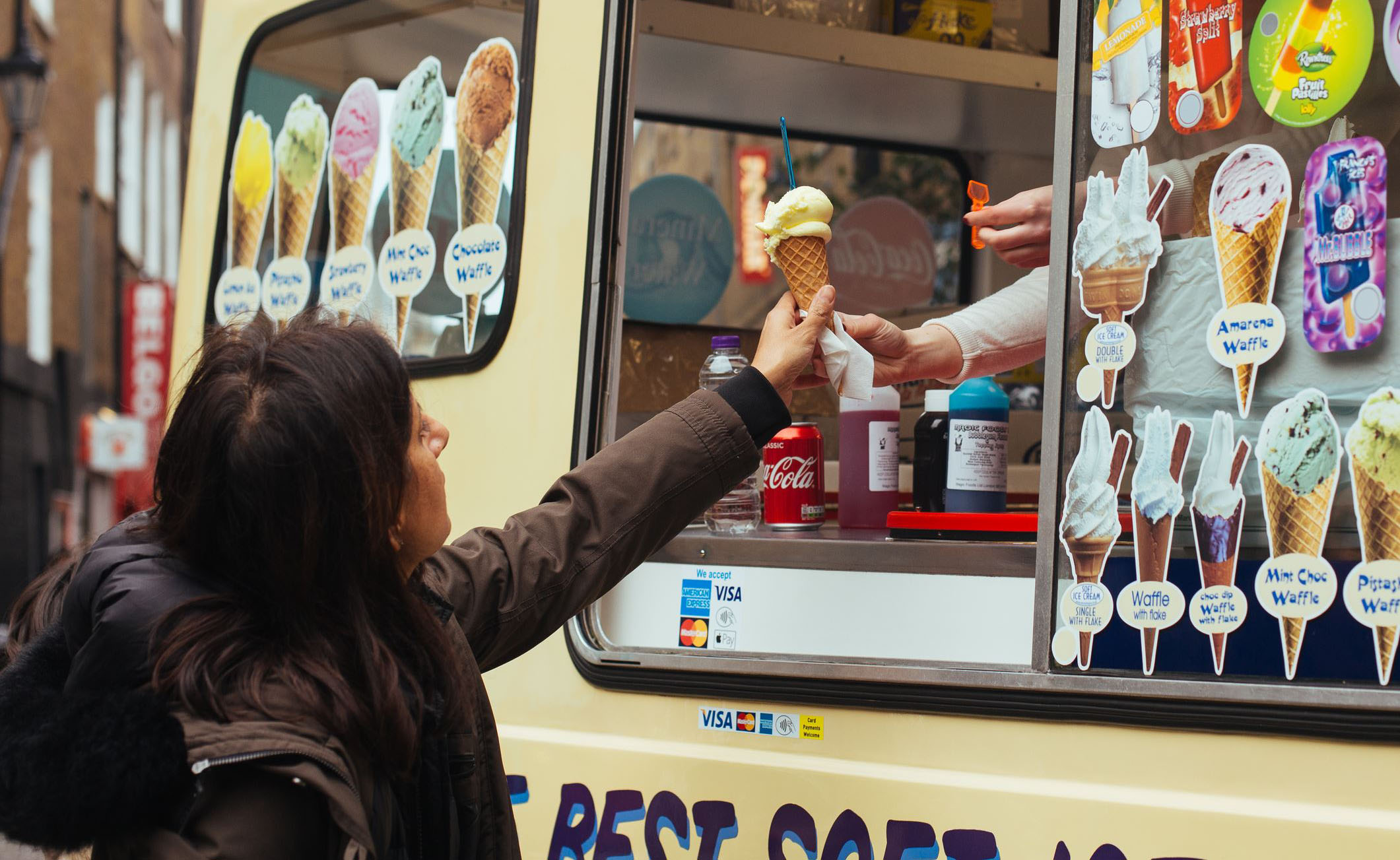 ice cream truck owner handing ice cream to a customer