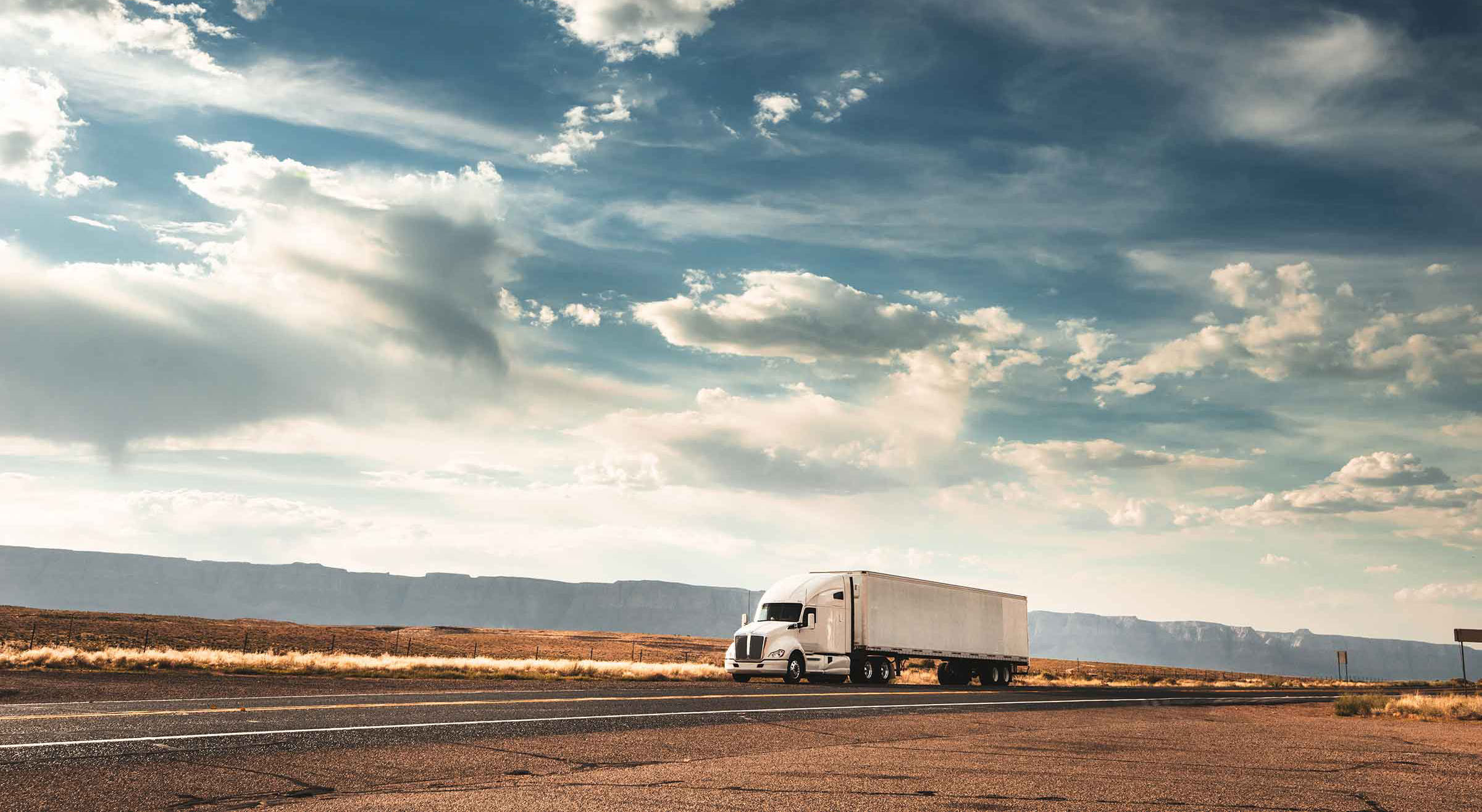 lone white long-haul truck on a deserted road