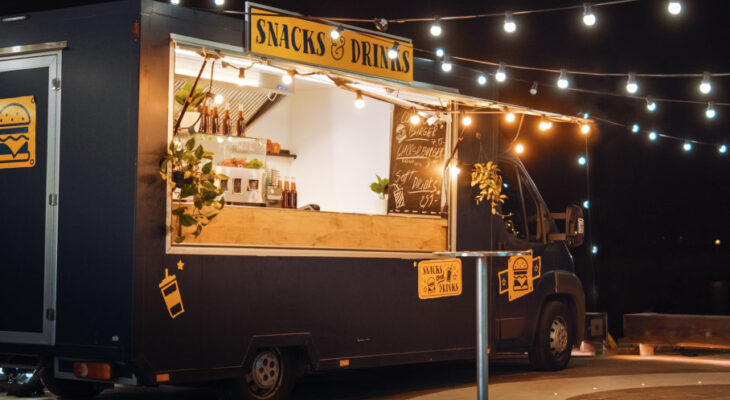 dark gray food truck selling snacks and drinks in the evening