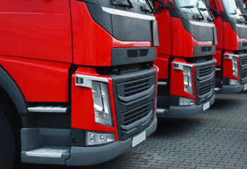 four semi-trailer trucks with red bumpers parked next to each other