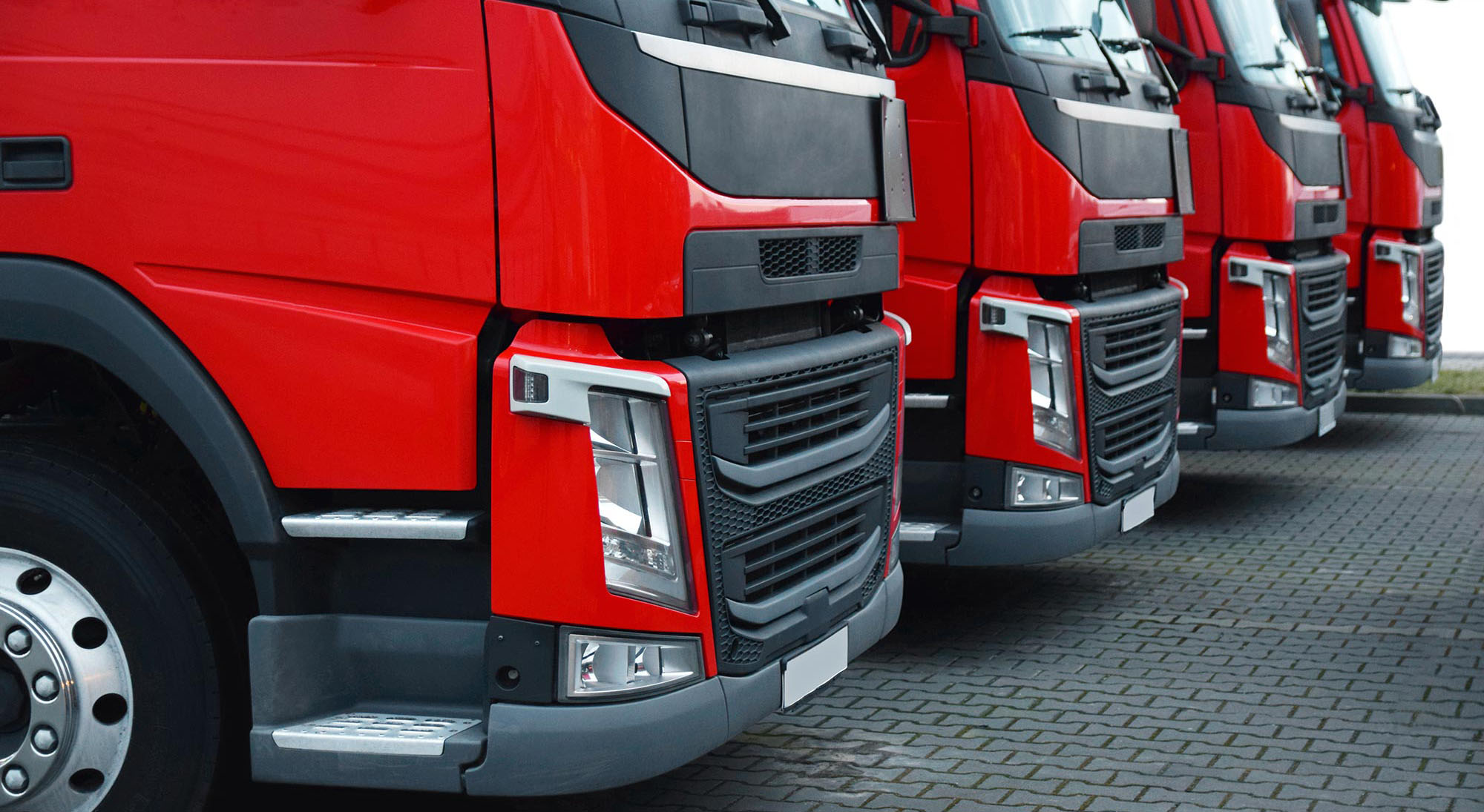 four semi-trailer trucks with red bumpers parked next to each other