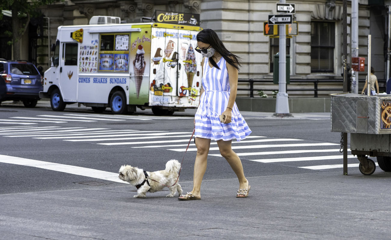 woman wearing a face mask during a pandemic with an ice cream truck in the vicinity