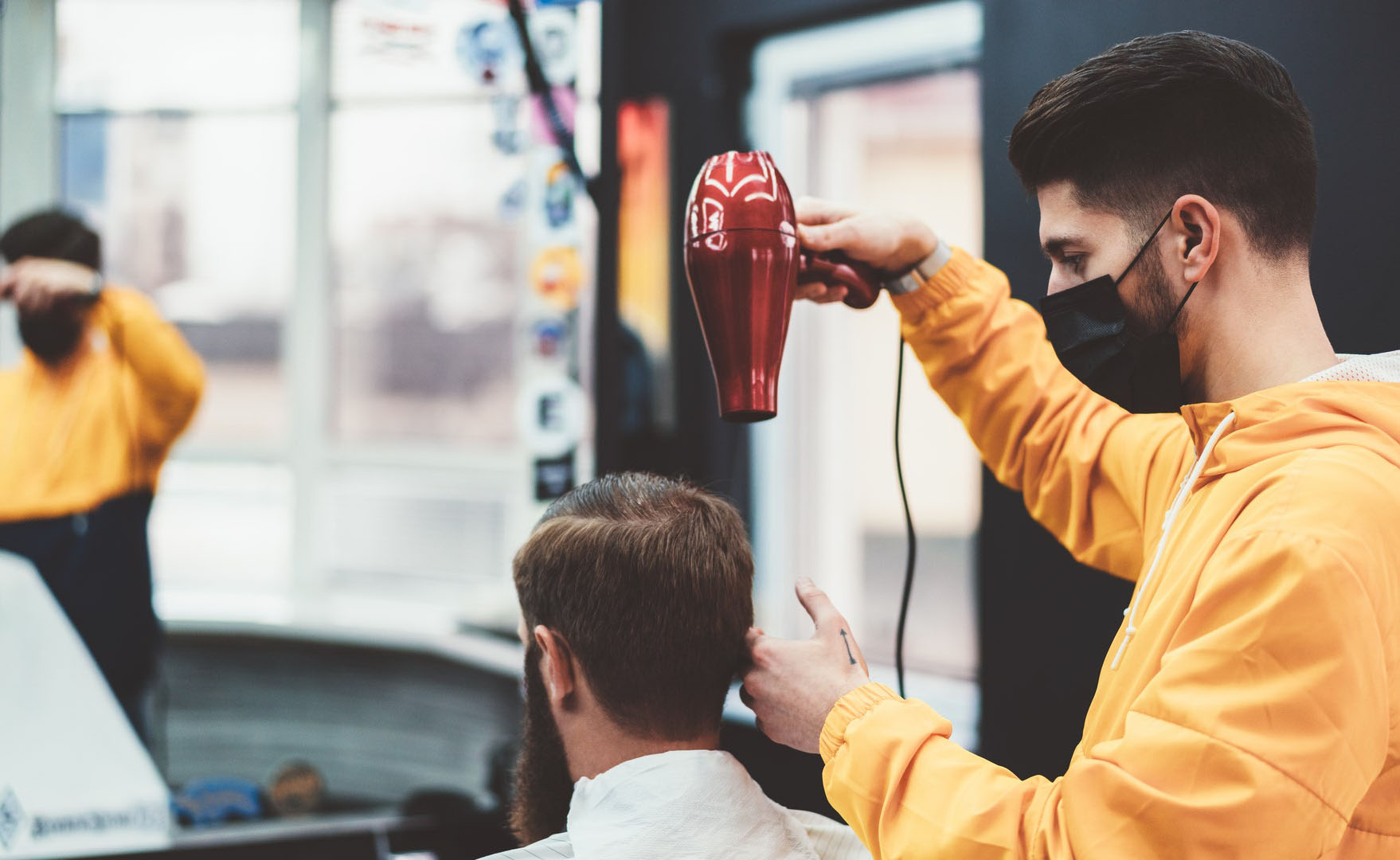 barber wearing a face mask during a pandemic while blow drying customer's hair