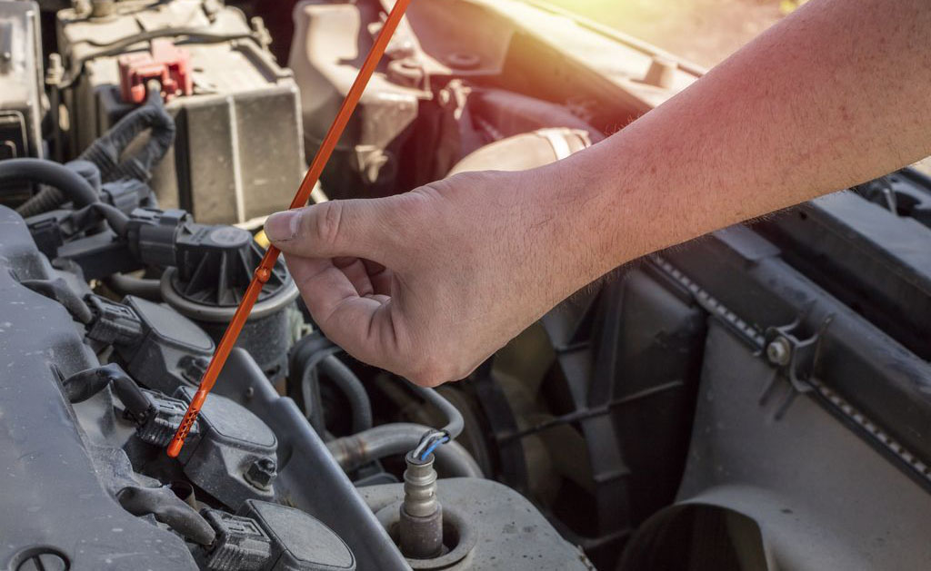man holding dipstick to check transmission fluid
