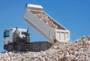 white dump truck unloading crushed rocks