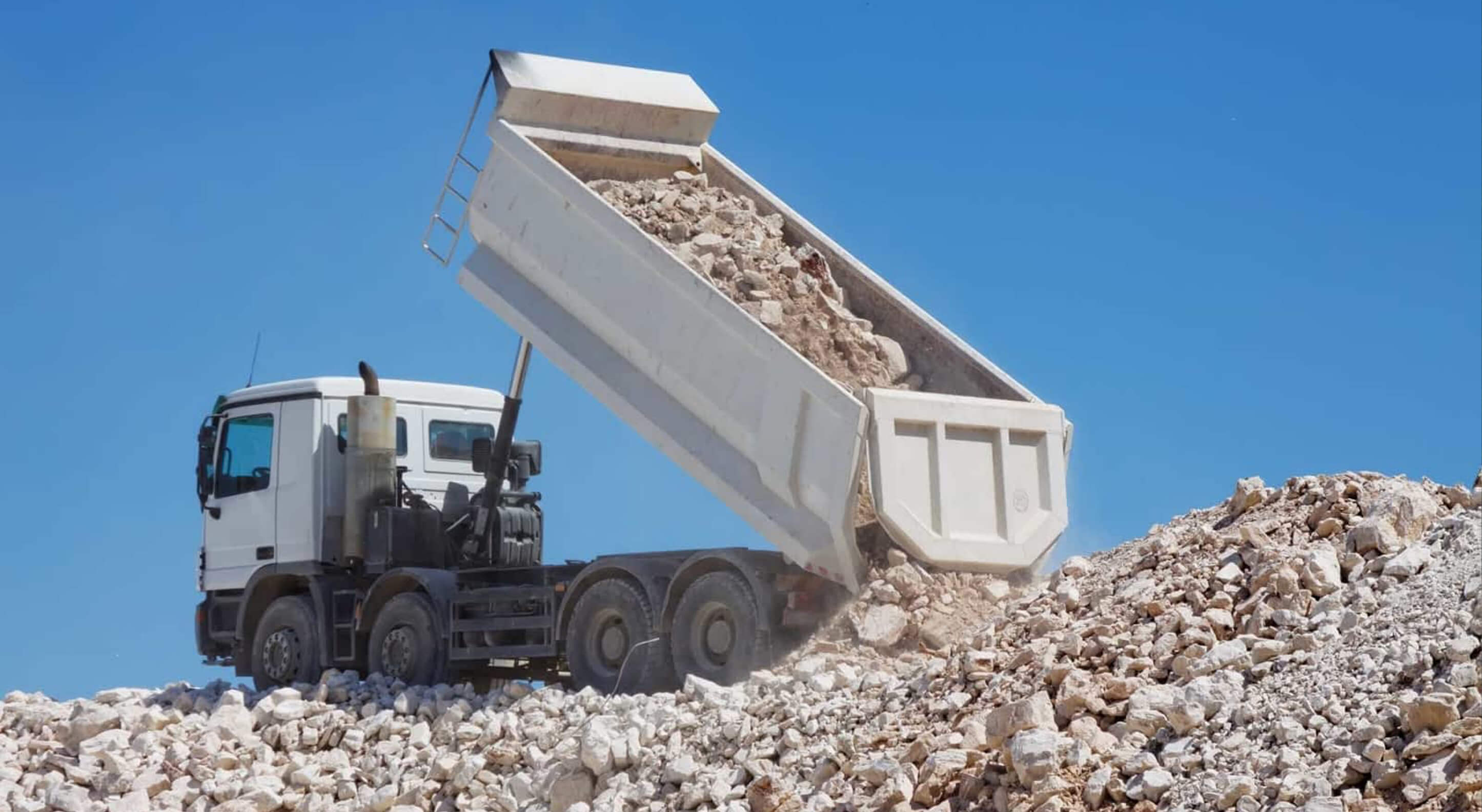 white dump truck unloading crushed rocks