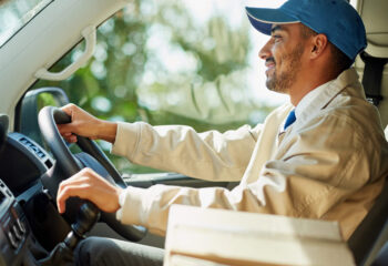 smiling delivery truck driver while holding gear stick