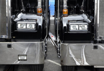 two black semi-trucks parked next to each other