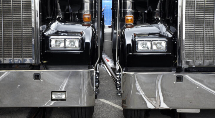 two black semi-trucks parked next to each other