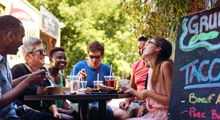 group of friends having lunch with food trucks at the background