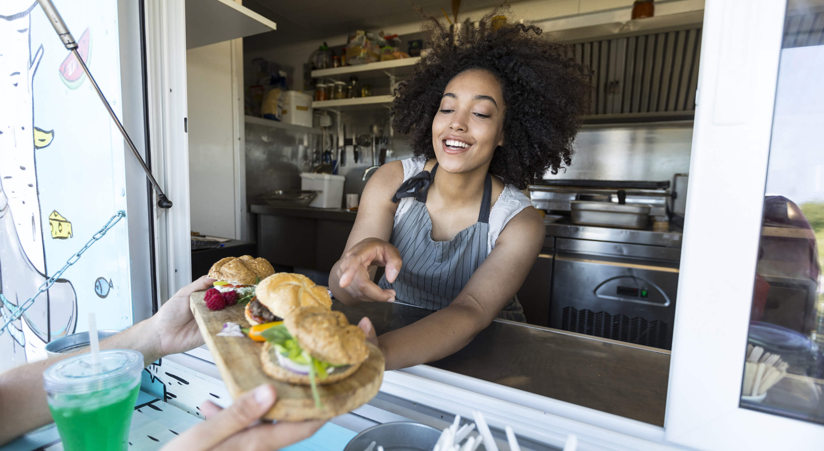 food truck owner giving an order of sandwiches and burgers to a customer