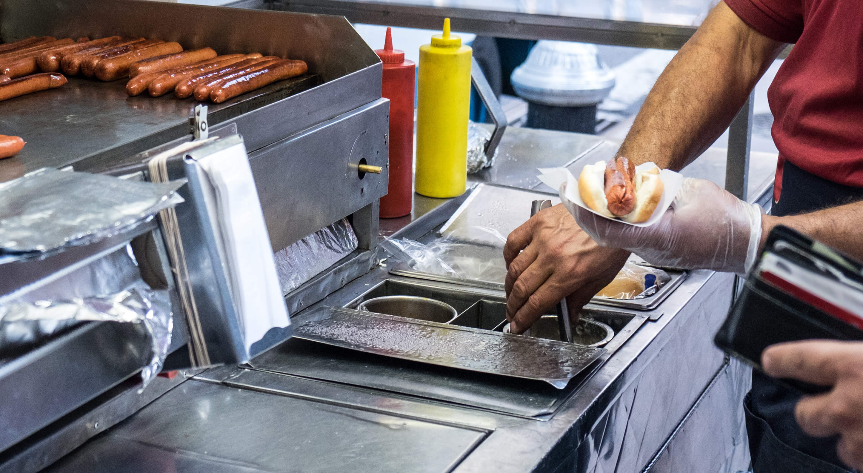 hot dog cart owner preparing a hot dog in New York City