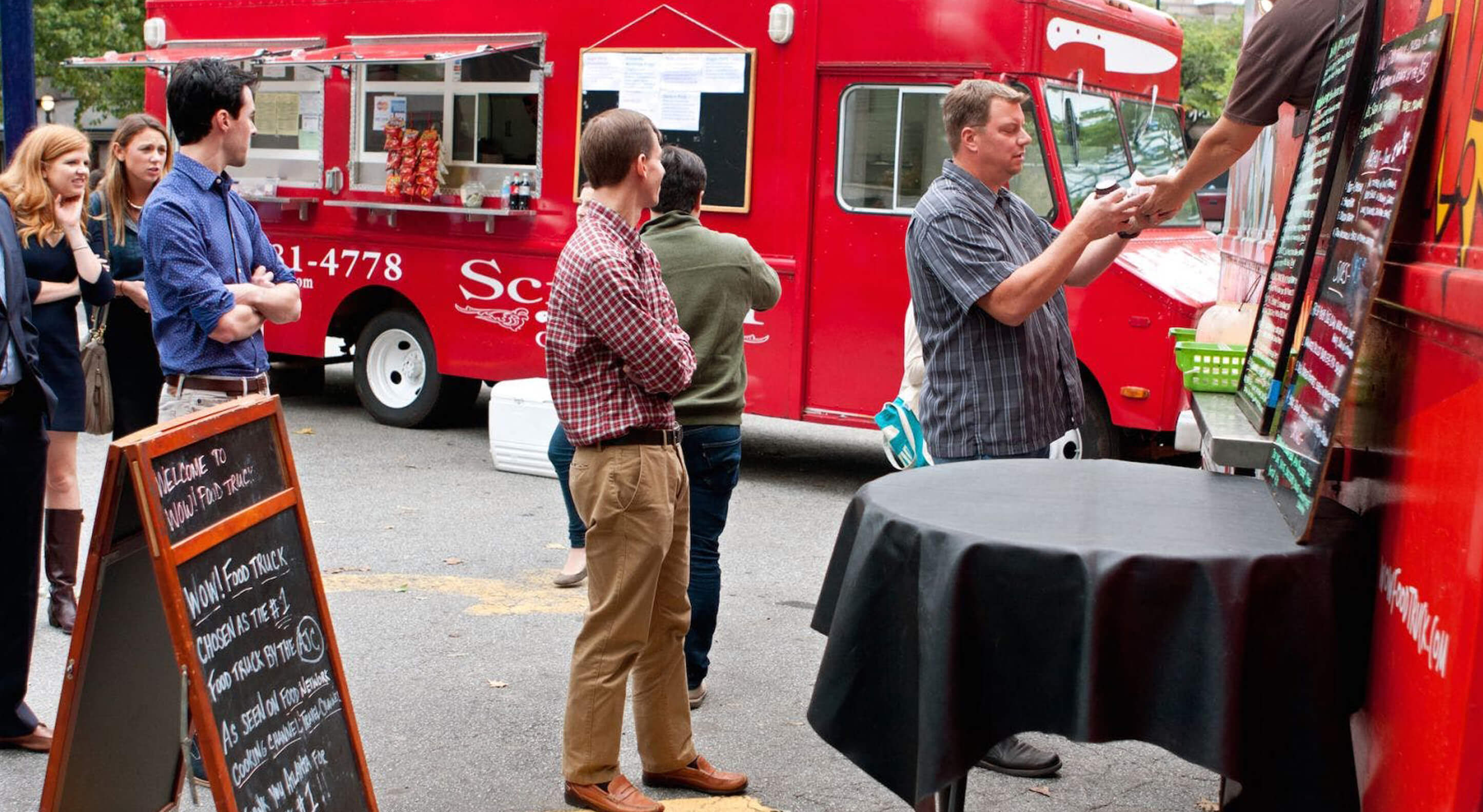 group of people lined up in front of a food truck