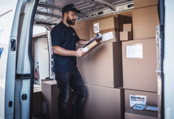 a young delivery man checking a list of packages inside a step van