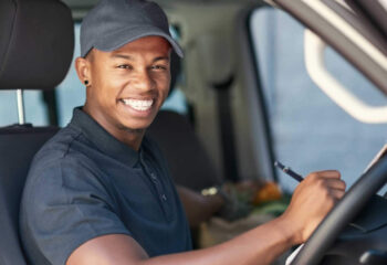 portrait of a courier writing on a clipboard while sitting in his stepvan