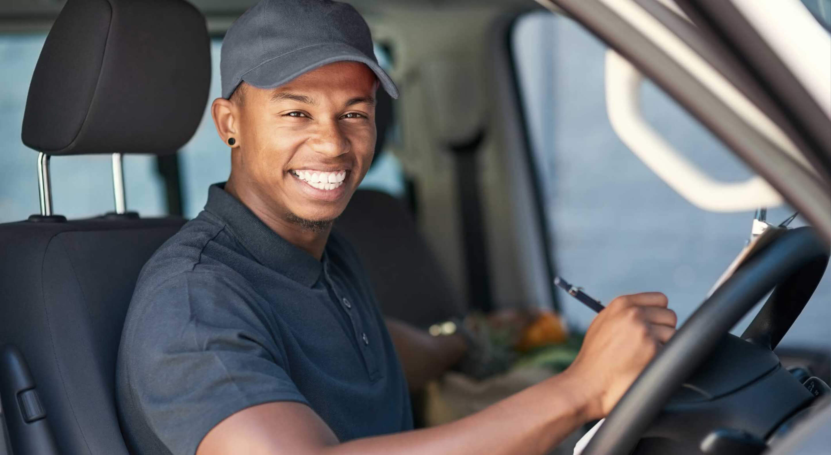 portrait of a courier writing on a clipboard while sitting in his stepvan