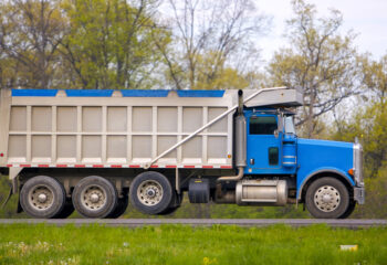 blue tarped dump truck in a grassy road