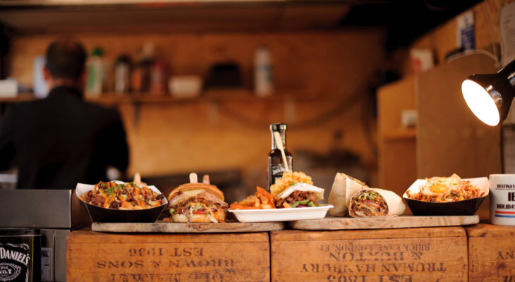 a line of burgers, fries, and burritos in a counter