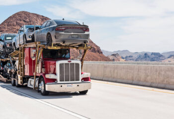 red semi-truck transporting a number of cars on a highway