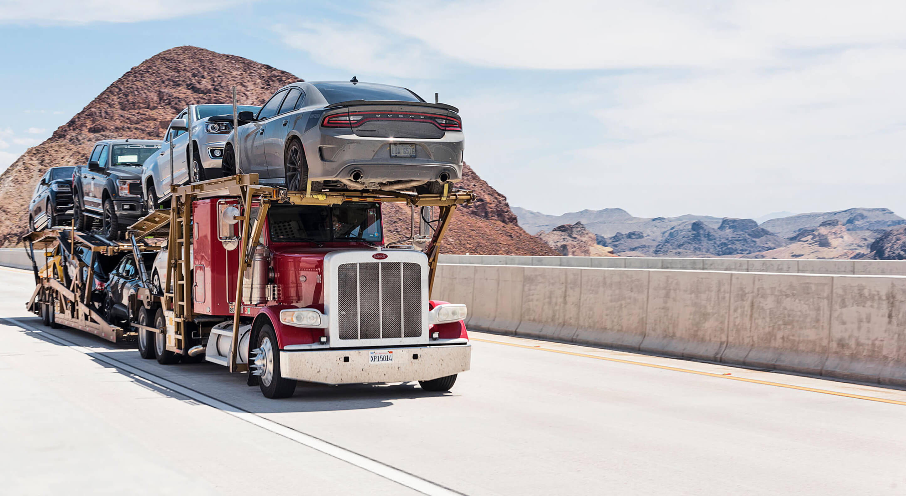 red semi-truck transporting a number of cars on a highway