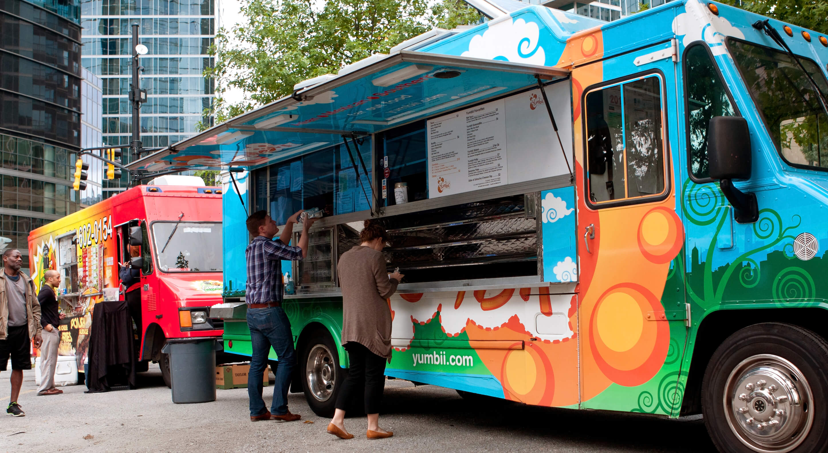 two colorful food trucks in a city center