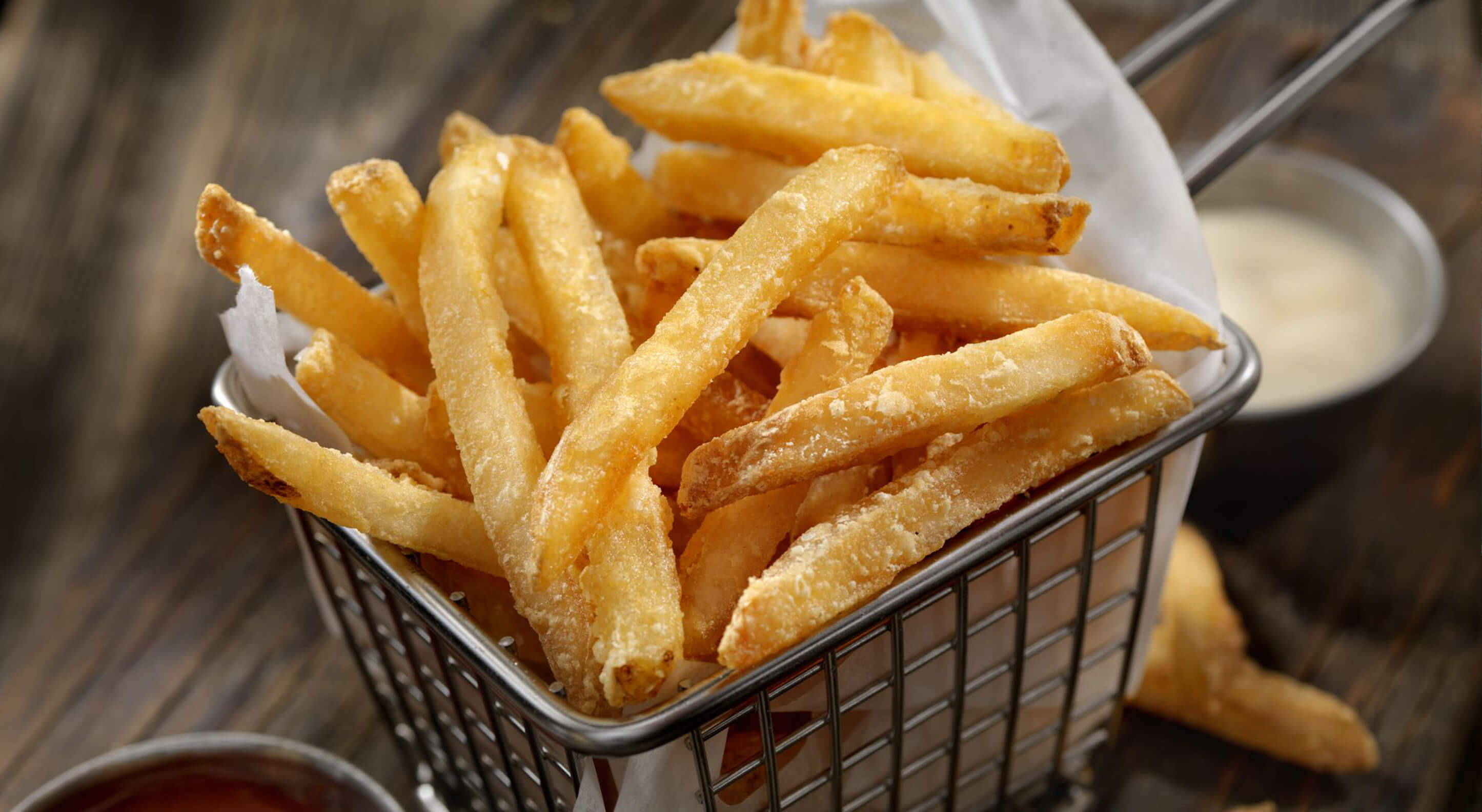 bucket of freshly cooked french fries with ranch dip on the side