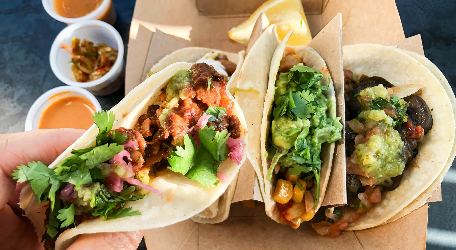 person holding halal corn tacos being sold in a halal food truck