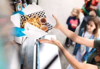 woman smiling as she receives her order of gourmet french fries with special dipping sauce at a food truck