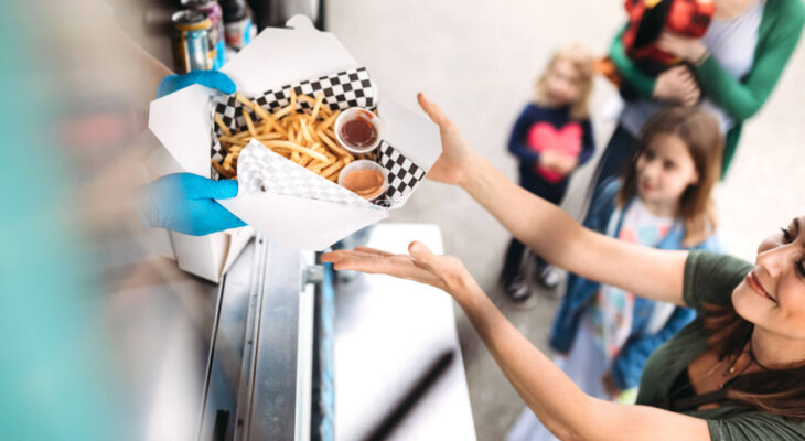 woman smiling as she receives her order of gourmet french fries with special dipping sauce at a food truck