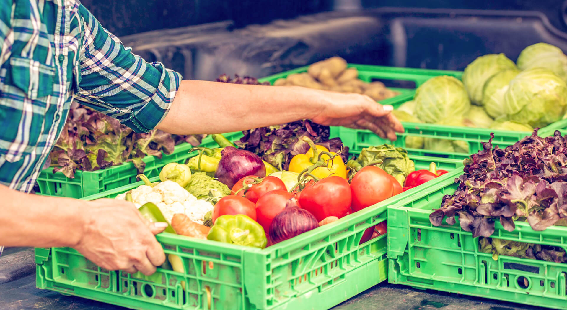 man holding a crate full of different kinds of vegetables in a mobile vegetable shop