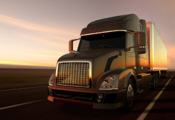 semi truck in a deserted road at dusk with visible truck lights