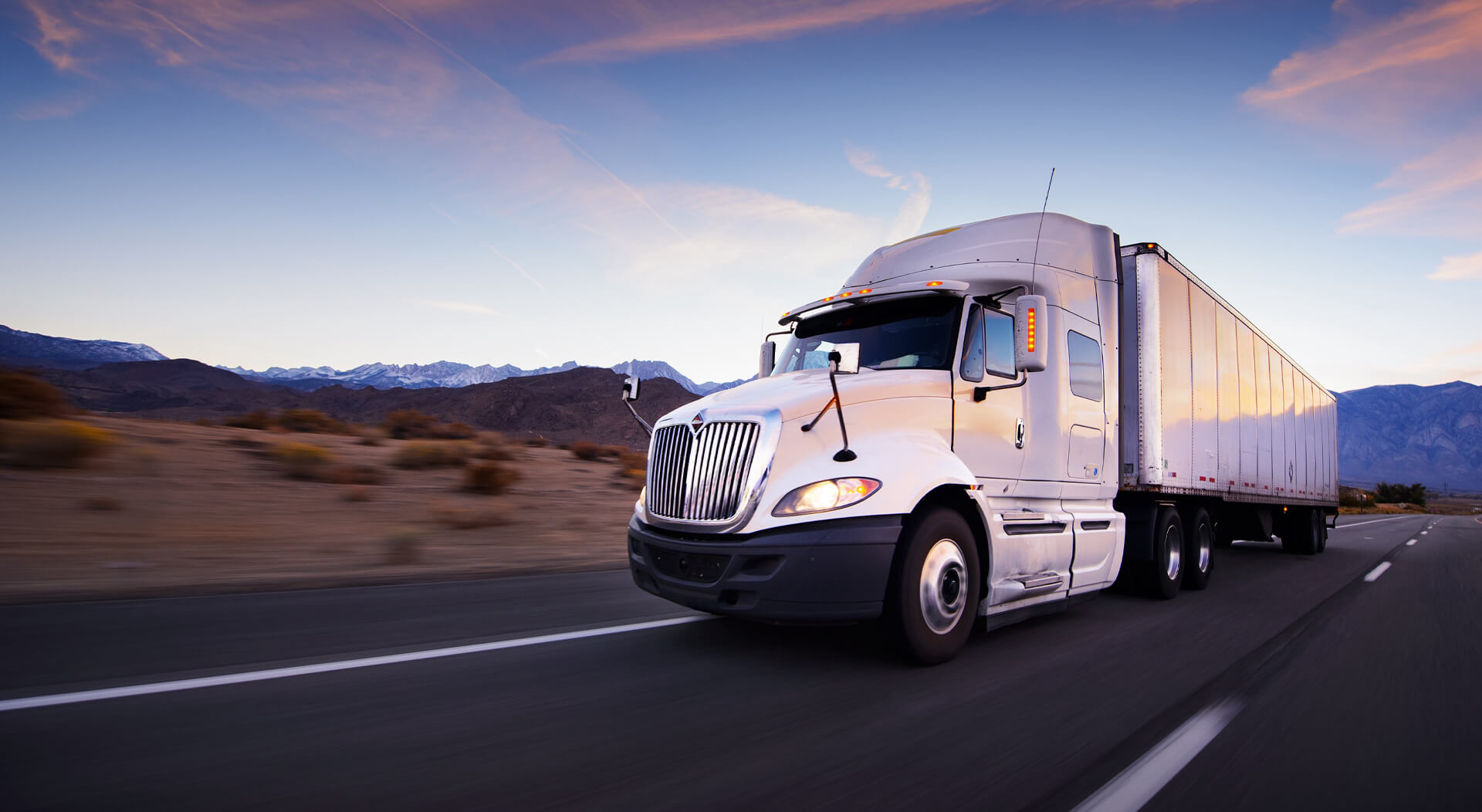 white trailer truck in a highway at dusk