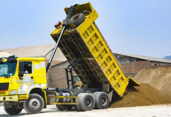 yellow dump truck delivering a load of dirt for a project at a construction site