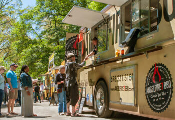 people standing in line to buy meals from a food truck lined up in a food truck festival