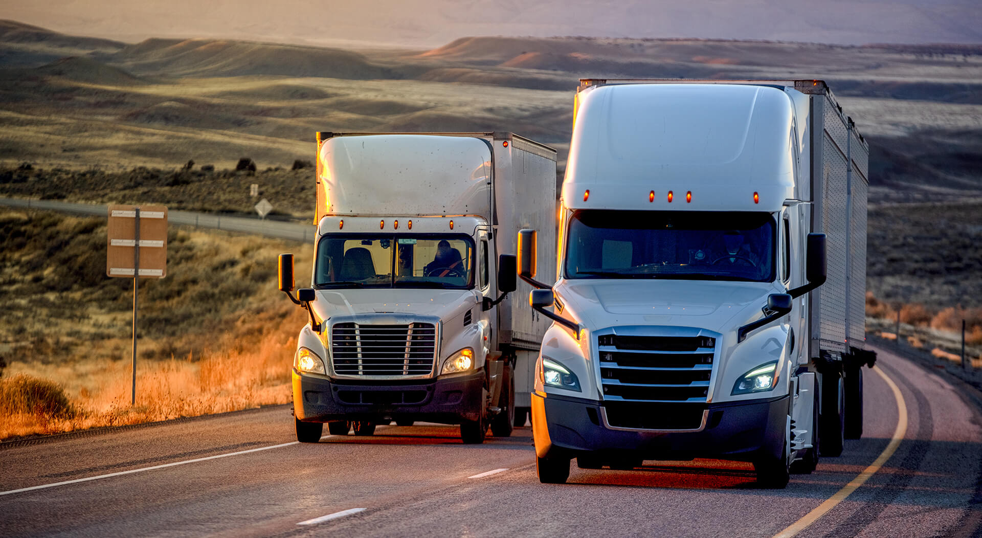 long haul semi-truck rolling down a four-lane highway at dusk