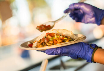 chef wearing gloves preparing tacos in a food truck